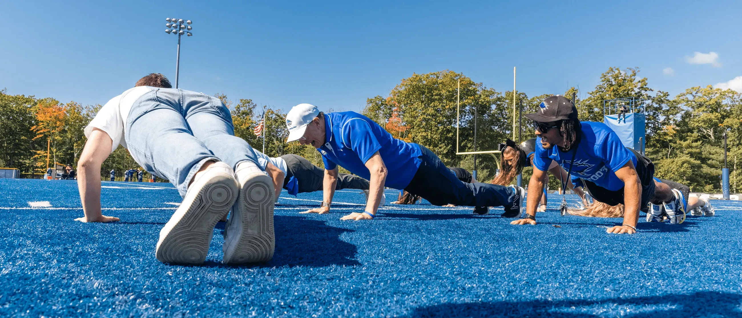 UNE President James Herbert does pushups on the sidelines of UNE's football field at Homecoming